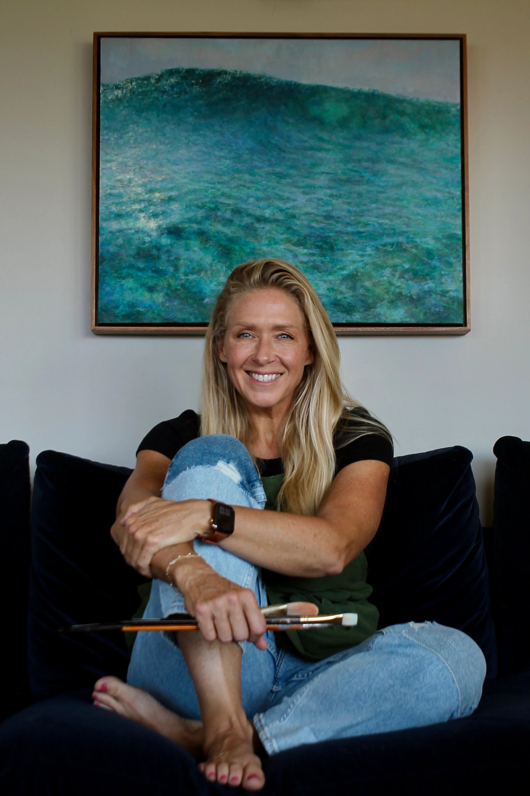Jill Weeks Smith seated in her San Diego home beside an original coastal painting