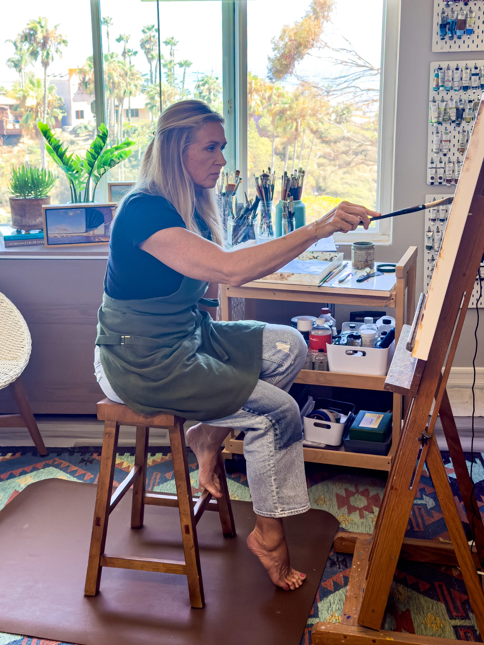 Jill Weeks Smith working on an oil painting from the side of her easel